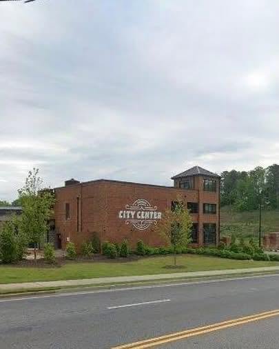 Brick building with City Center sign beside a roadway