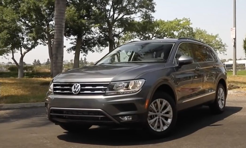 Gray Volkswagen Tiguan SUV parked on a paved road with trees in the background.