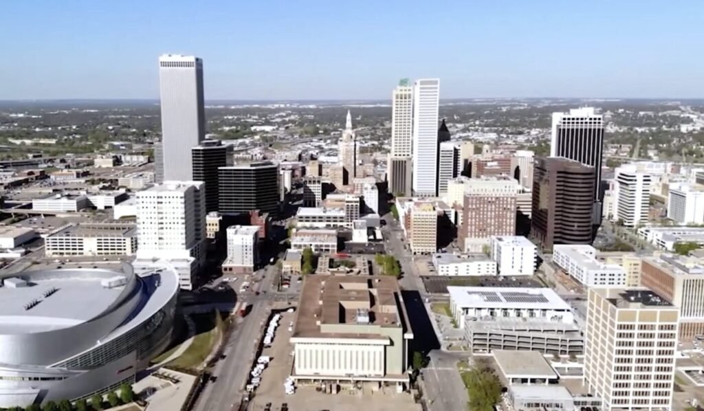 Aerial view of downtown Tulsa with office towers and a large arena.