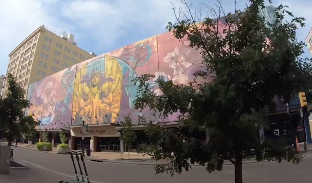 A colorful mural covers the side of a downtown Tulsa building beside a mostly empty street.
