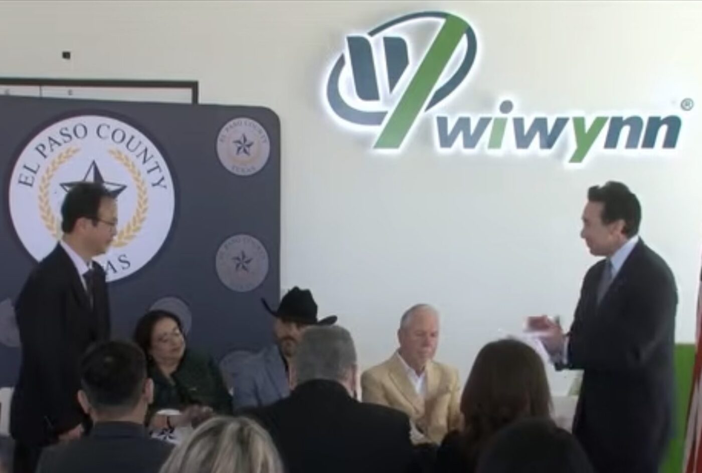 People seated indoors during a Wiwynn event, with a large Wiwynn logo on the wall behind them.