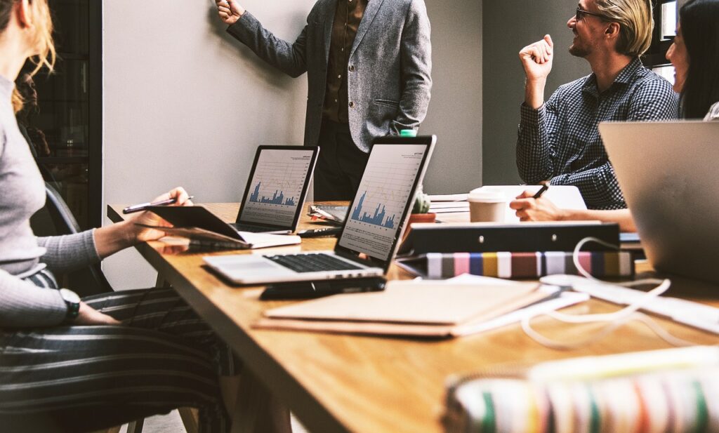 People in a meeting around a conference table with laptops and notebooks