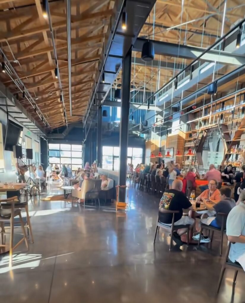 Large restaurant interior with high ceilings, exposed beams and people seated at tables