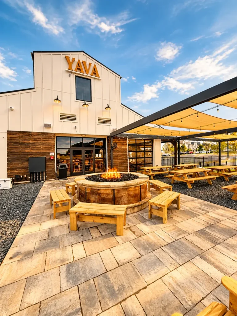 Outdoor patio with picnic tables and a fire pit in front of the YAVA building