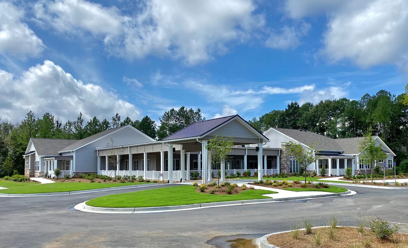 Exterior of the Champions Place residence with a covered entrance and landscaped driveway.