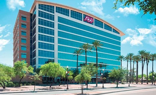 ADP office building with glass windows, palm trees and a blue sky.