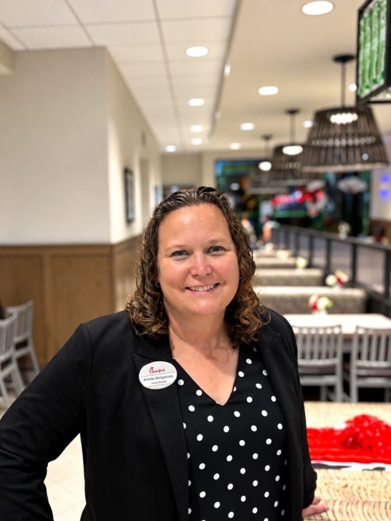 A woman stands inside a Chick-fil-A restaurant, wearing a black blazer and polka dot blouse.