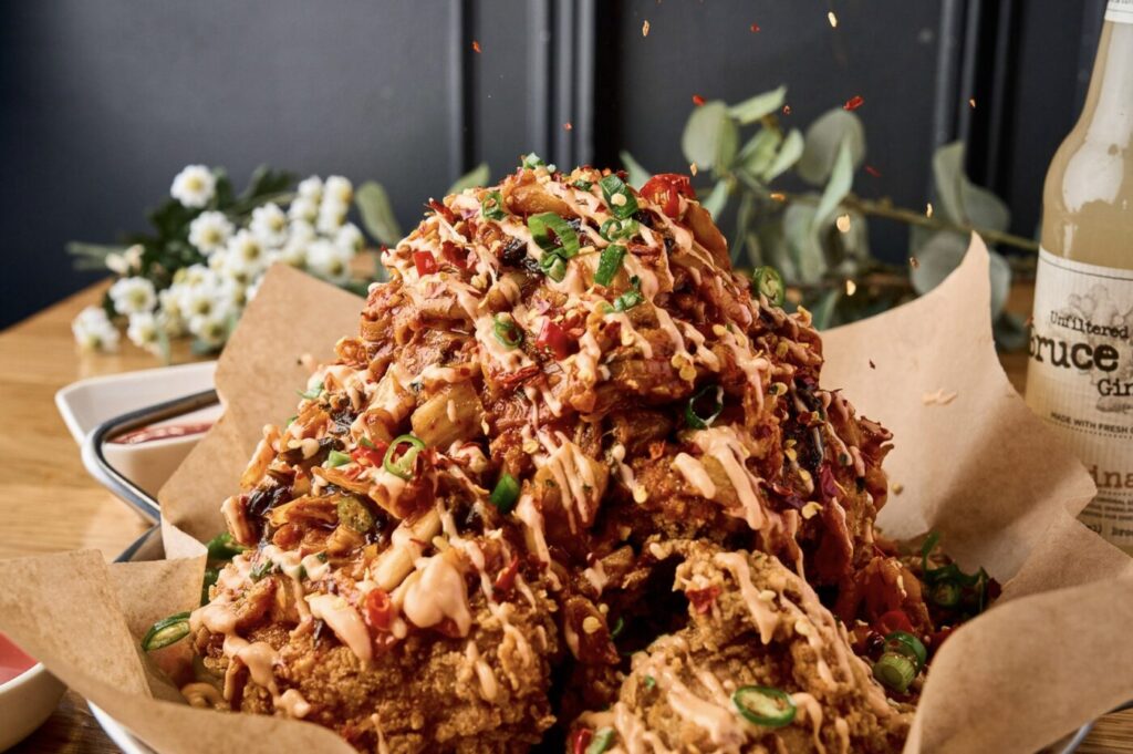 A mound of fried chicken topped with a glossy red sauce and sliced green onions.