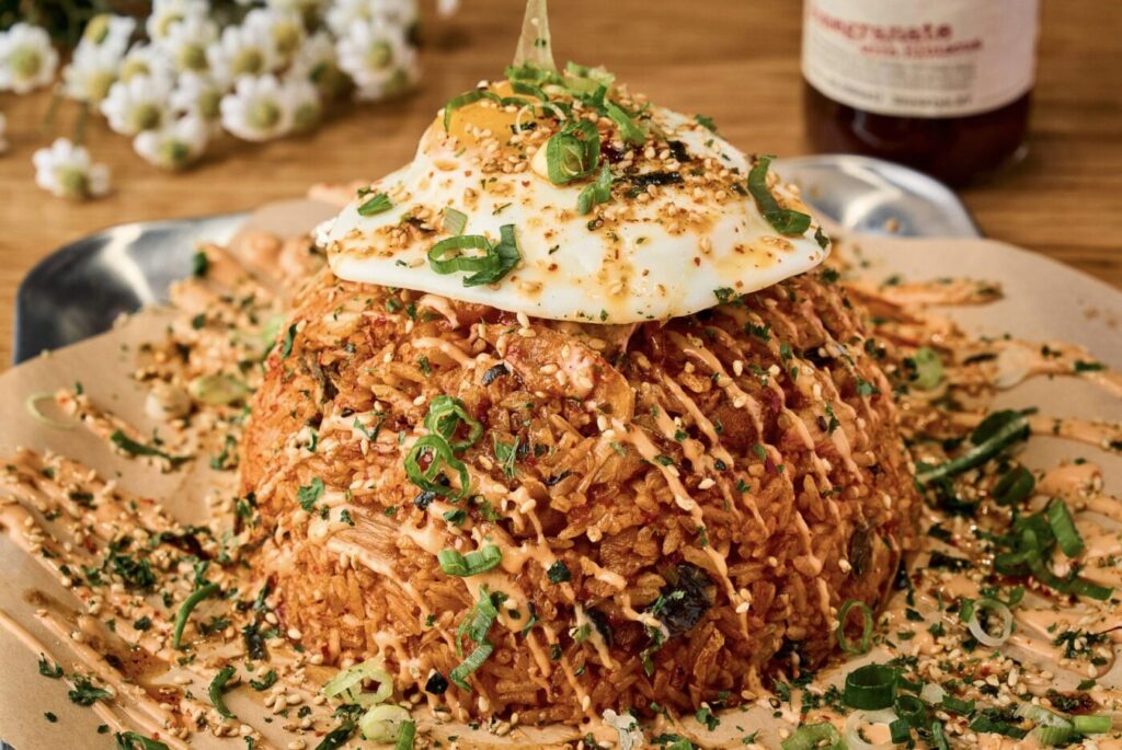 A mound of kimchi fried rice topped with a fried egg and green onions.