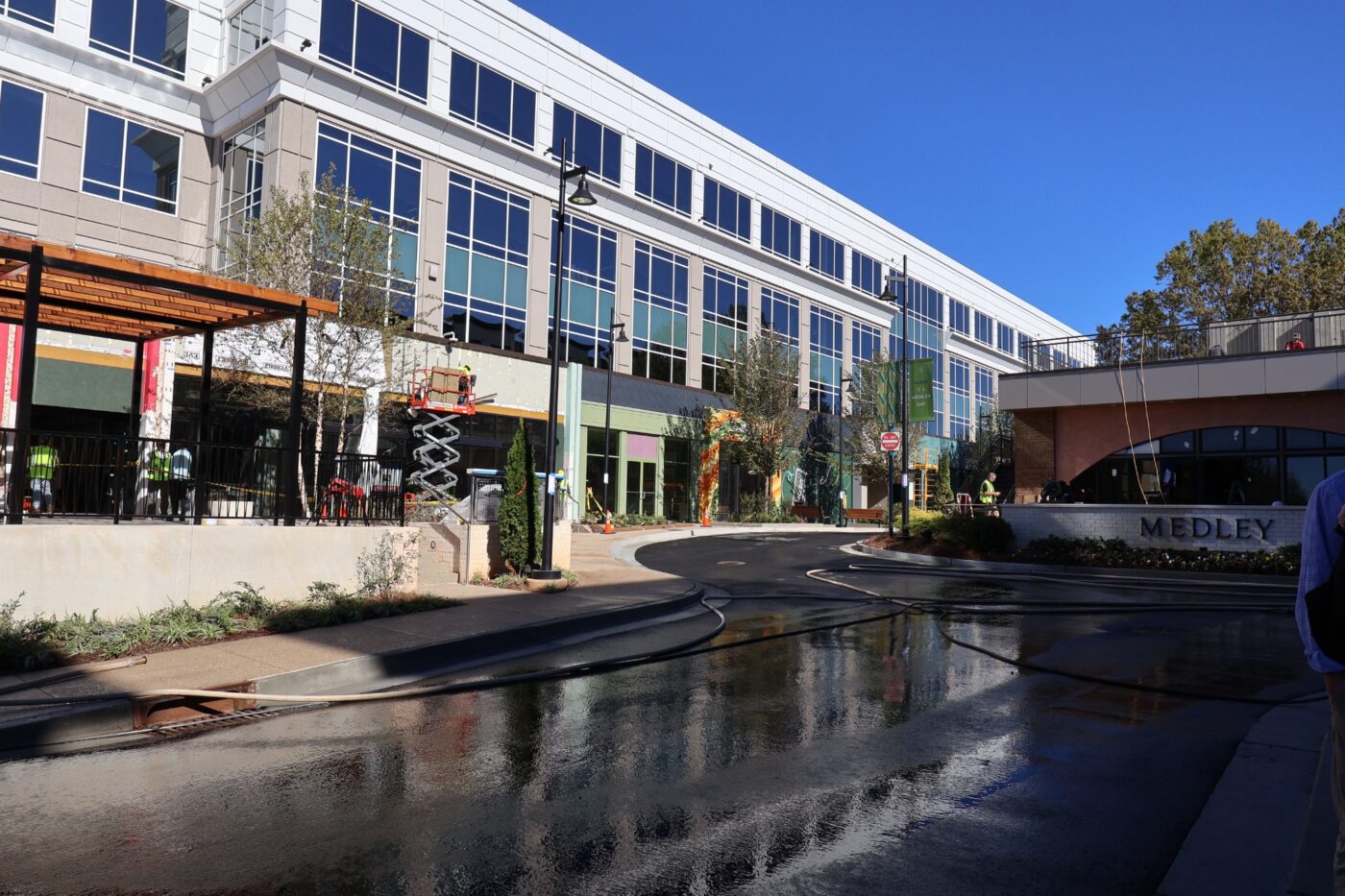 A long white building with ground-floor construction and lifts beside a Medley street.
