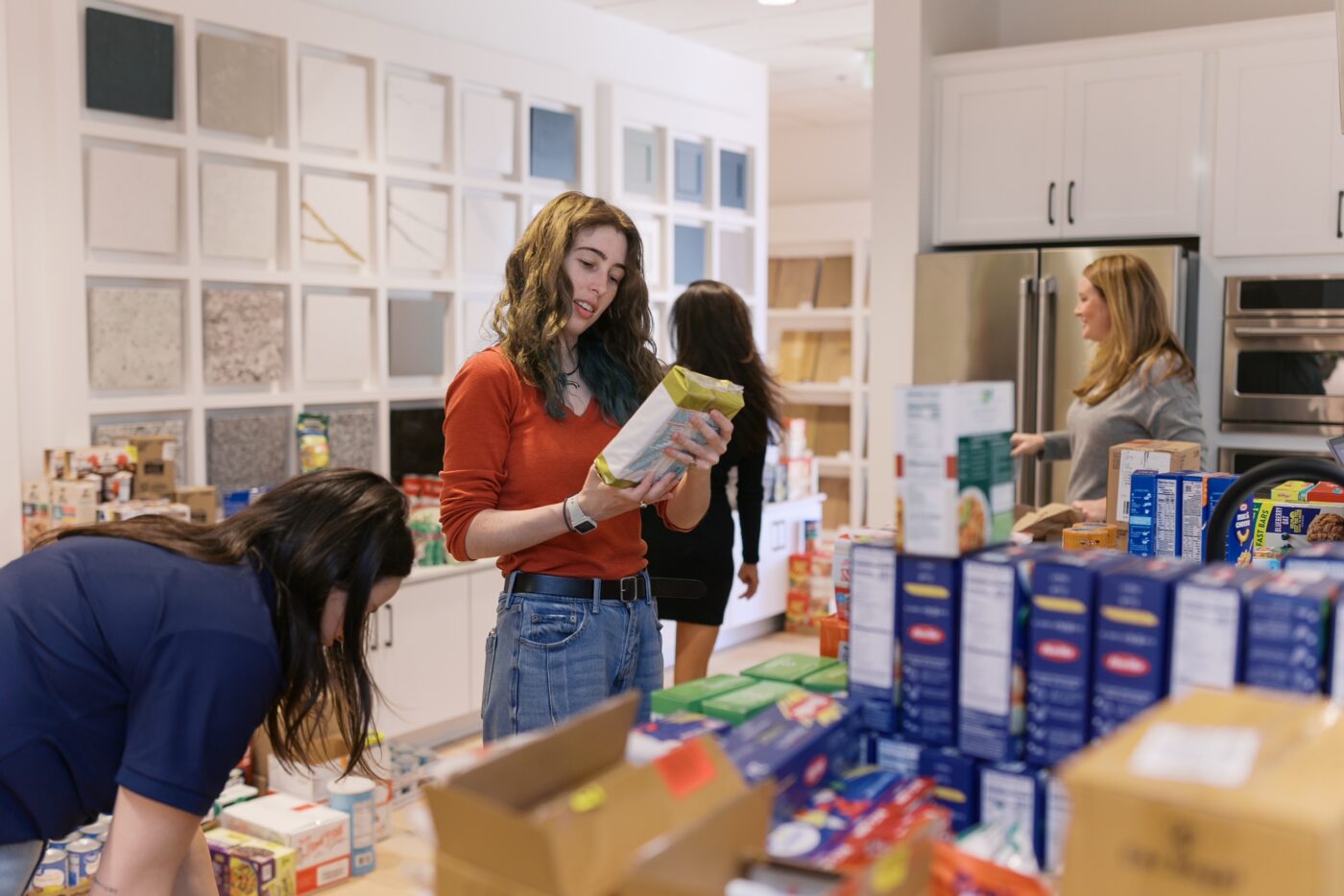 People sort packaged food donations on counters in a showroom.