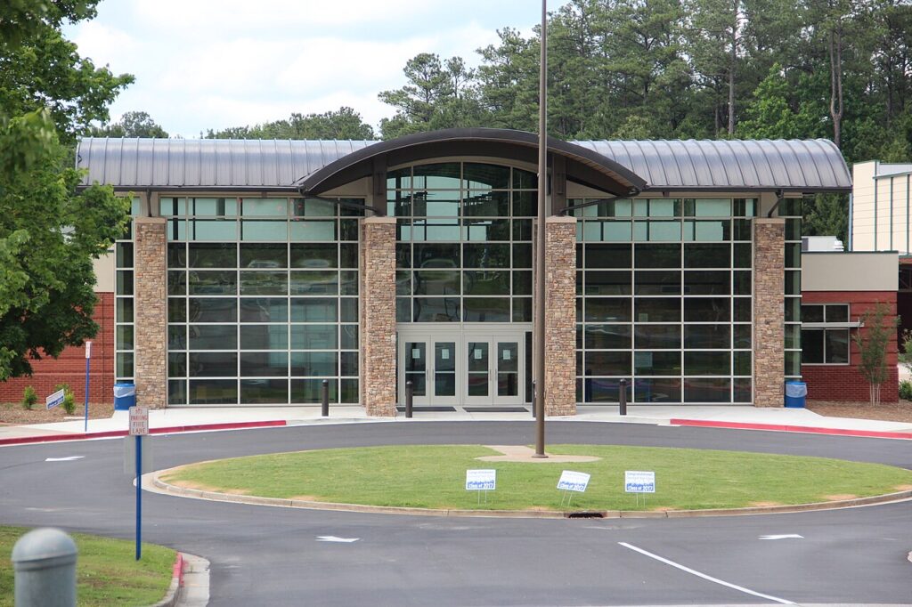 Front entrance of a school building with large glass windows and a curved roofline