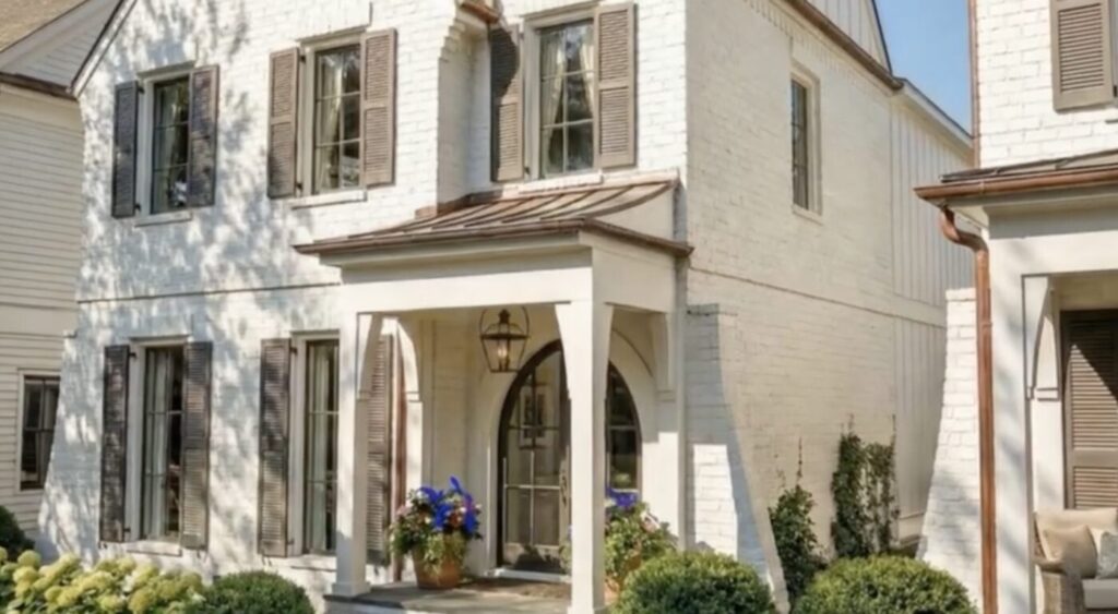 A two-story house with white brick, shutters and a covered front porch.