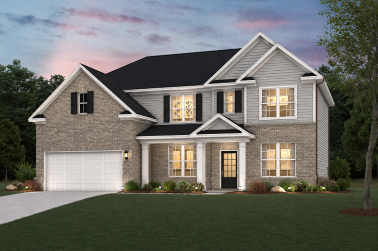 Two-story suburban house with a two-car garage, brick and siding exterior, and lit windows at dusk.