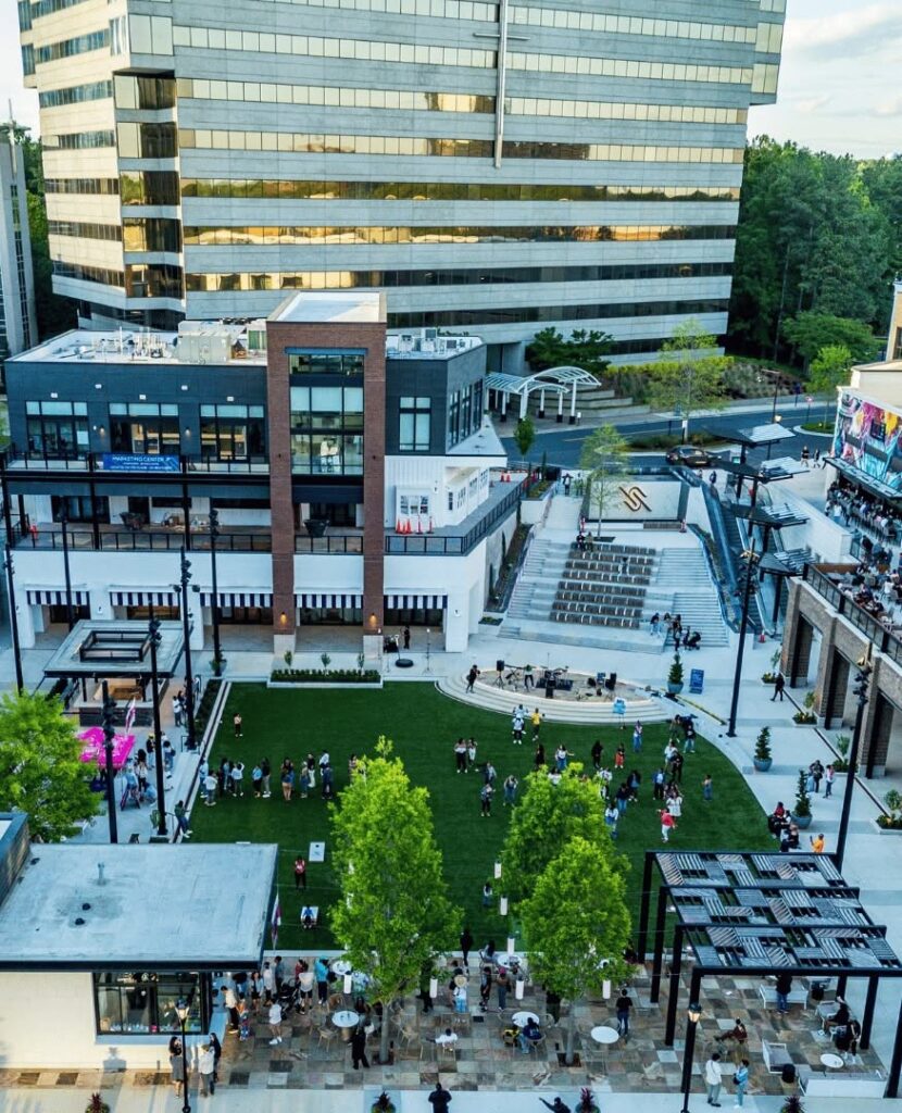 An elevated view shows a landscaped plaza with a lawn, steps and surrounding commercial buildings at High Street.