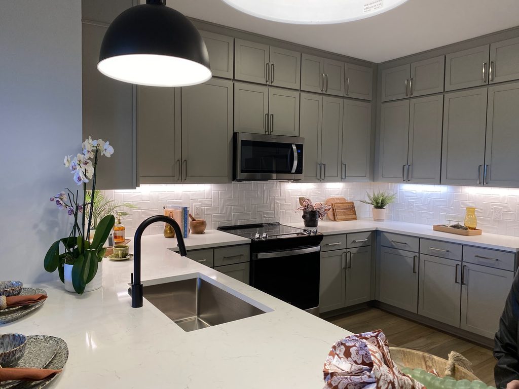 Kitchen at Prelude in Medley, with gray cabinets, white countertops, a stainless steel sink and black pendant lights.