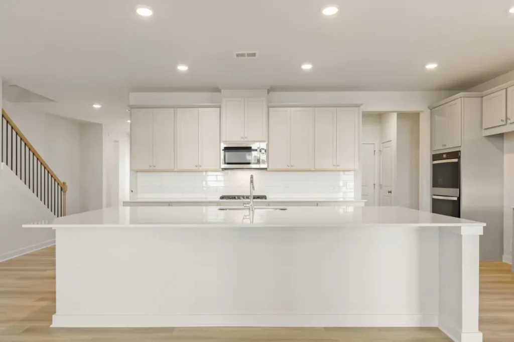 Bright kitchen with white cabinets, large island and recessed ceiling lights