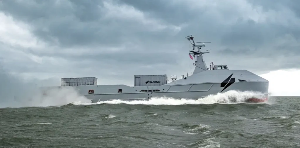 A gray high-speed vessel speeds across choppy water under dark clouds.