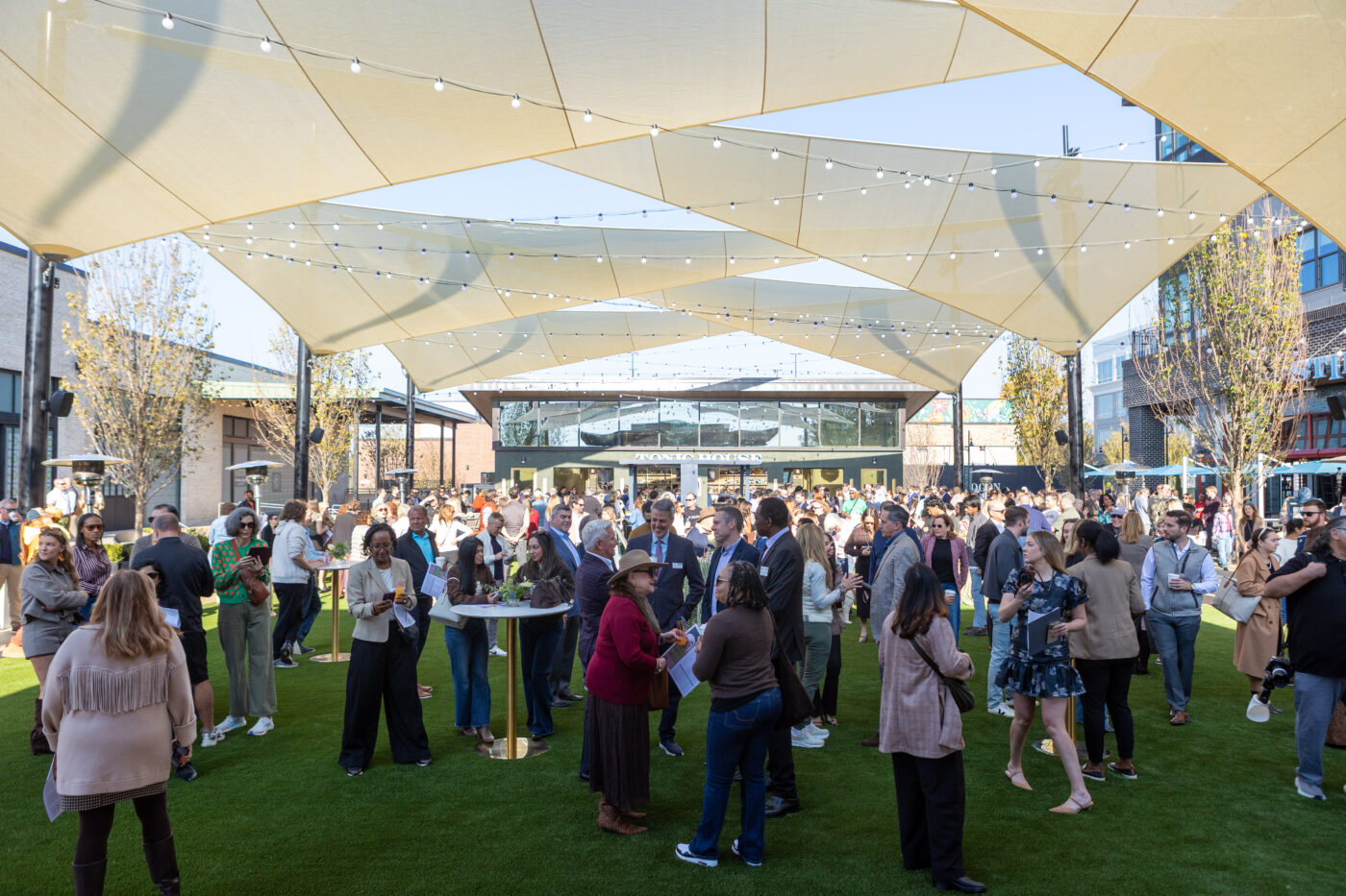 Visitors gather on the lawn beneath shade canopies at Medley’s Plaza.