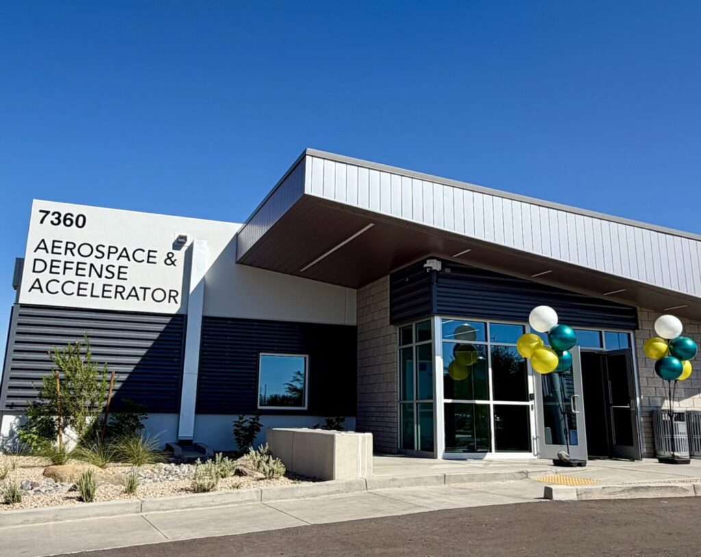 Exterior of a modern building with a sign reading Aerospace & Defense Accelerator and balloons by the entrance.