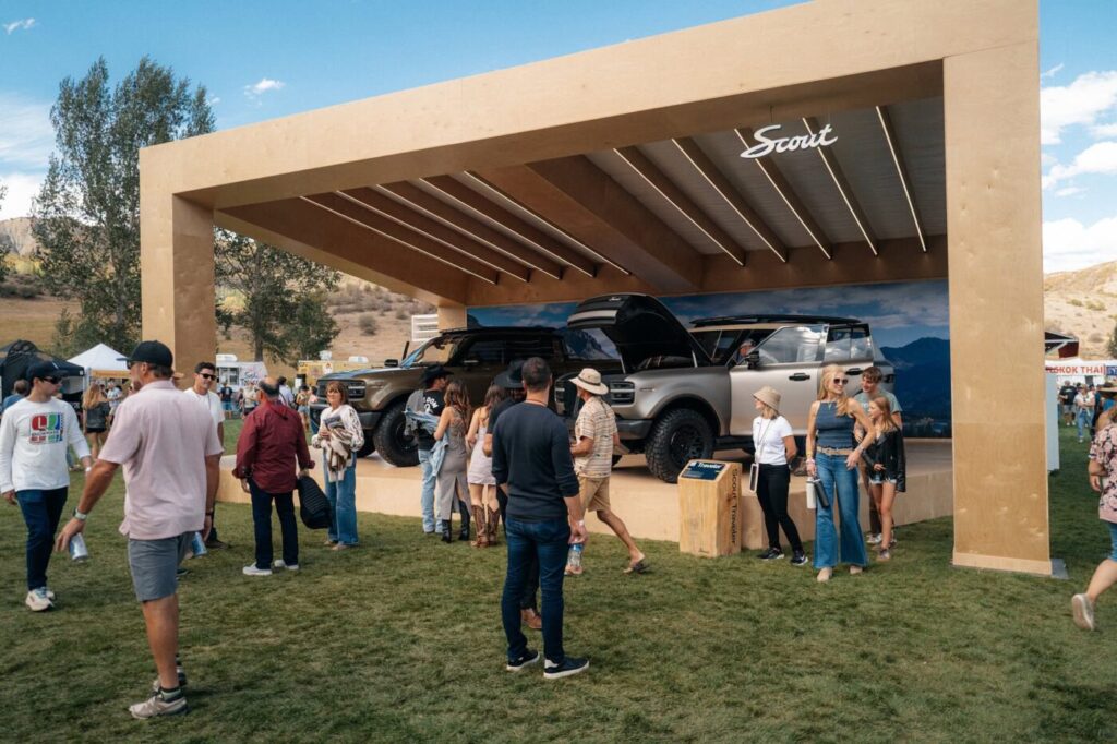People gather around two Scout vehicles on display outdoors