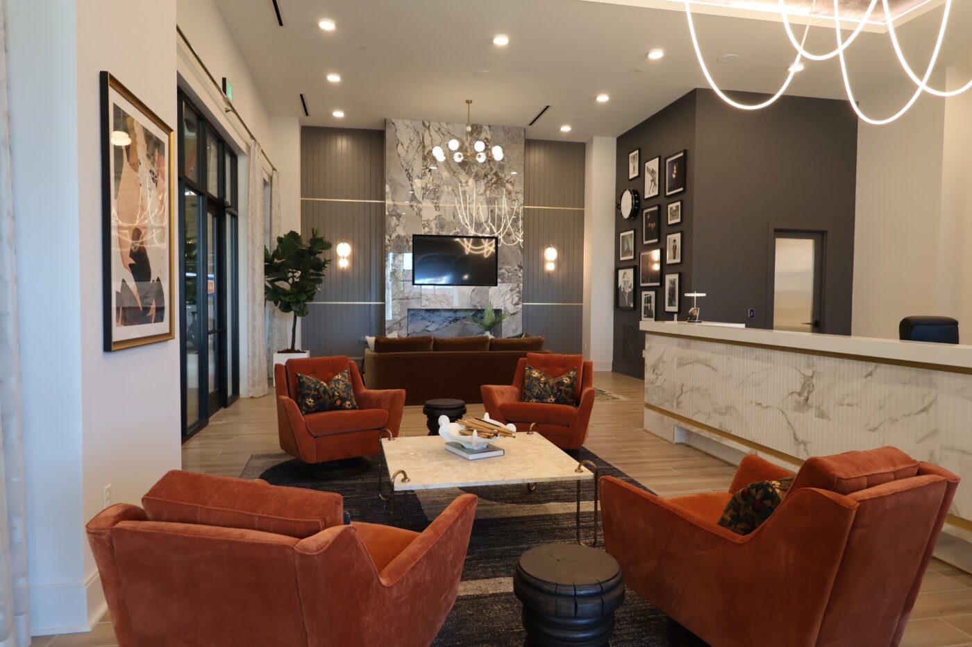 Orange armchairs, a fireplace and a reception counter inside the Prelude apartment lobby.
