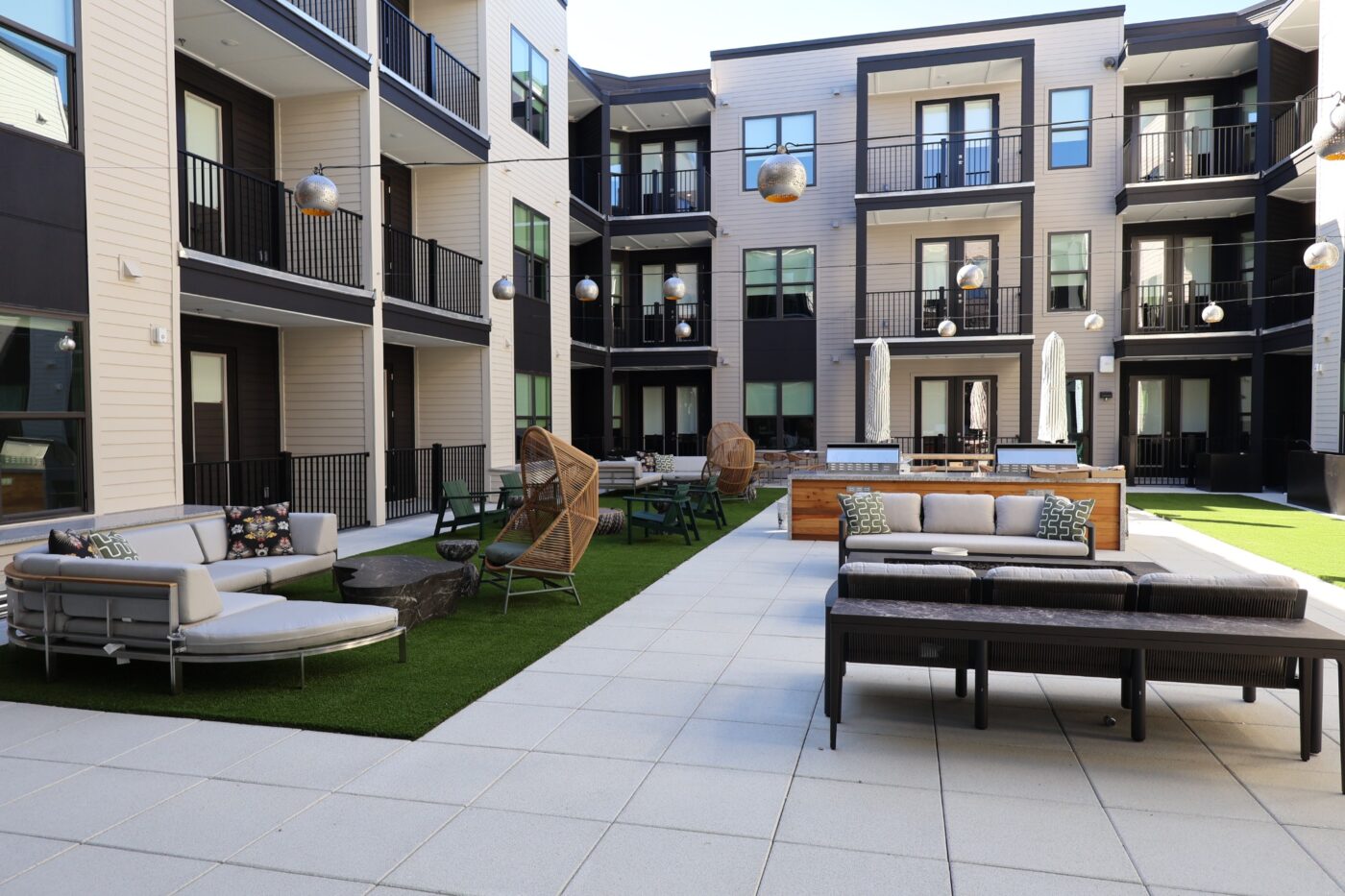 Outdoor seating, grills, turf and hanging lights in a Prelude residential courtyard.