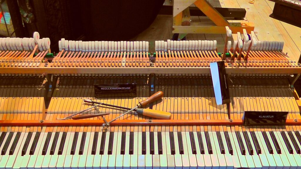 Open piano with the keyboard exposed and tuning tools resting on the action