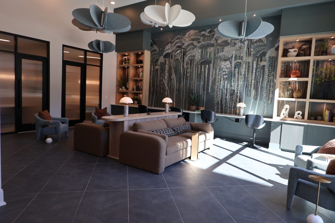 Prelude coworking room with desks, upholstered chairs, floral wallpaper and pendant lights.