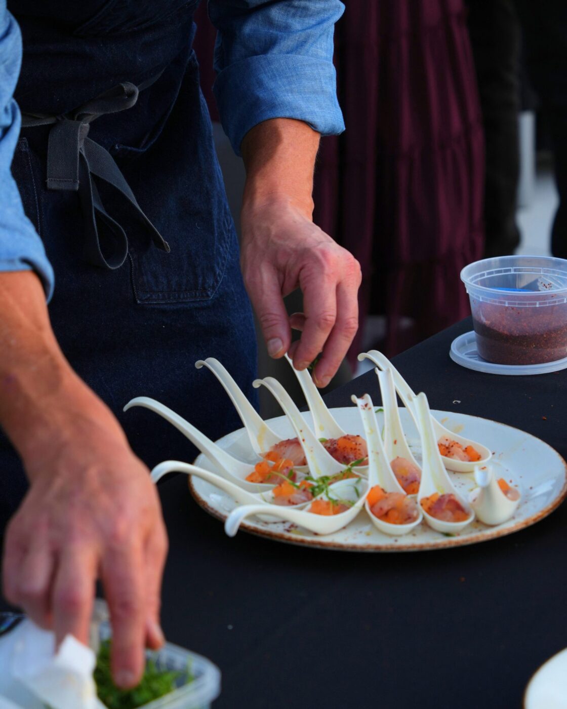 A server arranges bite-size food samples in white tasting spoons at Taste Brookhaven.