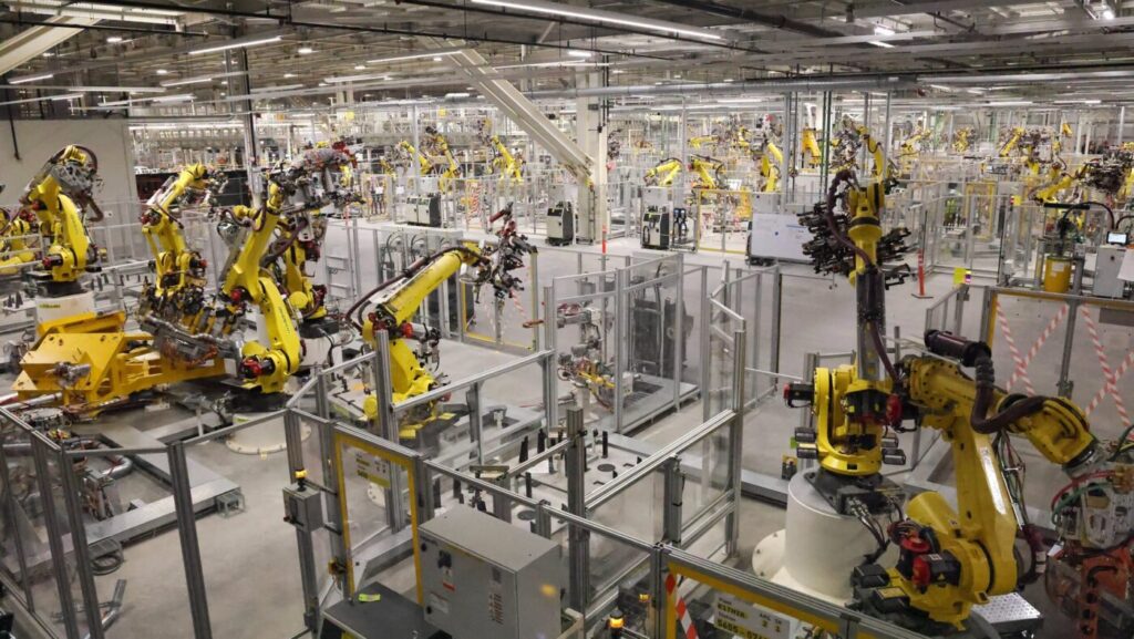 Rows of yellow robotic arms inside an auto assembly plant