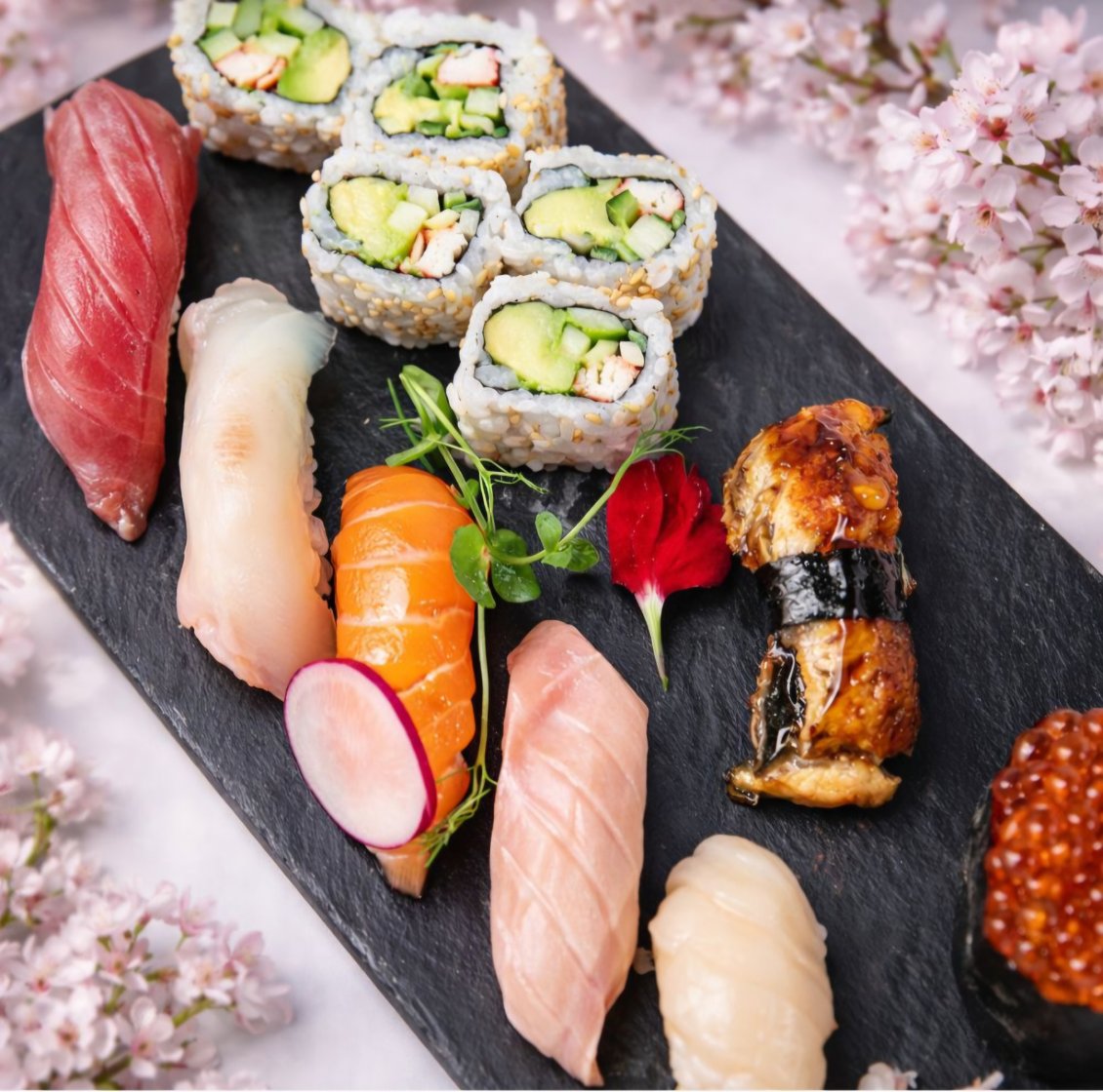 Sushi rolls and nigiri arranged on a black platter at Tomo