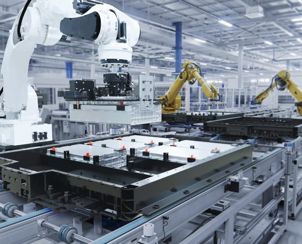 Automated robotic arms working over a manufacturing assembly line in a bright factory.